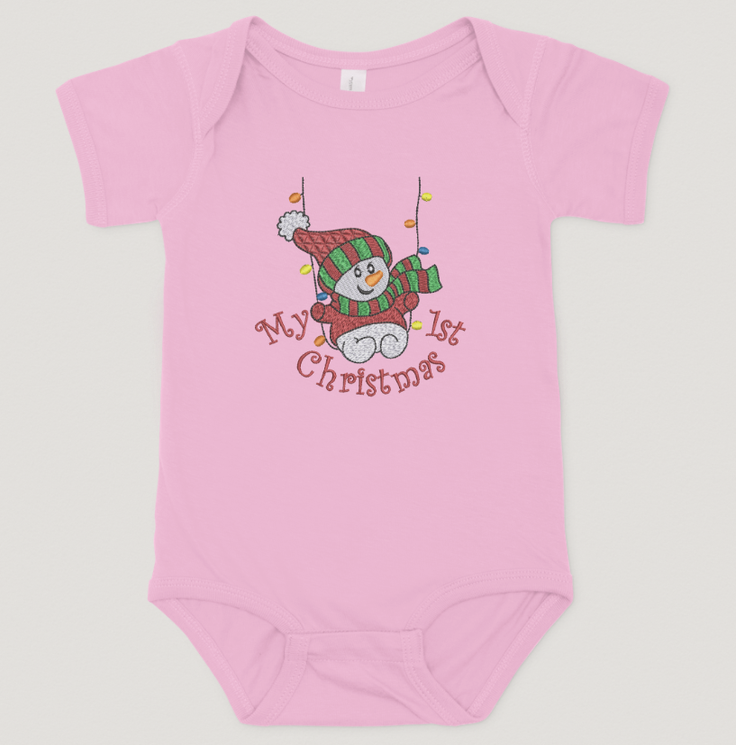 Pink baby onesie with a snowman design and 'My 1st Christmas' text on a light gray background